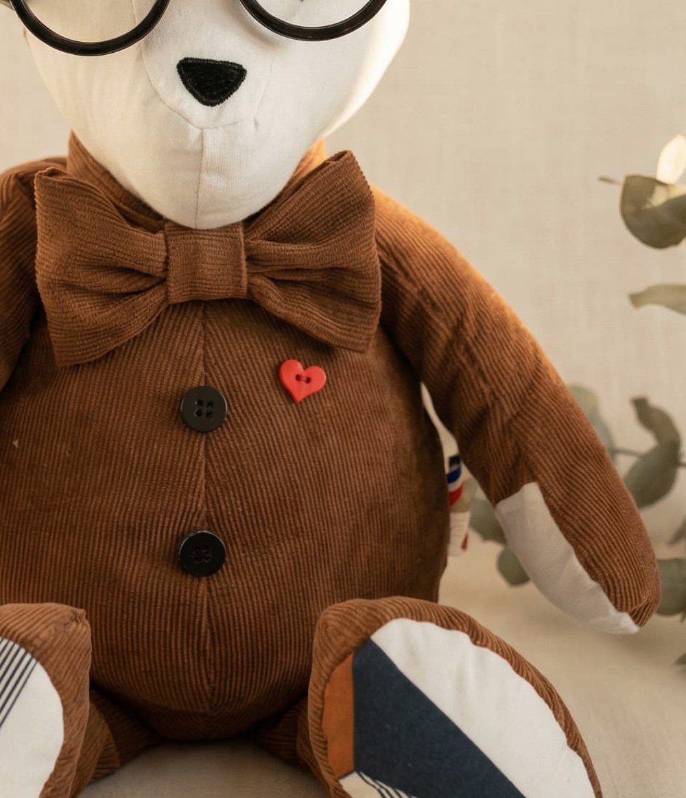 Gros plan sur le bouton-cœur rouge, les boutons et la texture en velours côtelé d'un ours de mémoire